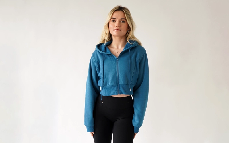 a women wearing blue color cropped zip up hoodie