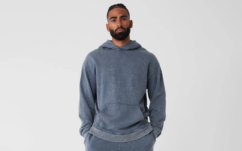 A man wearing a dark gray vintage wash hoodie
