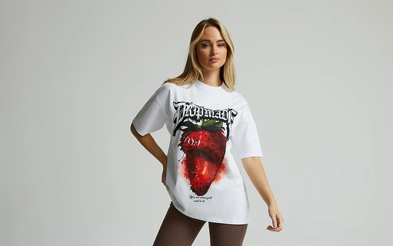 A women wearing a pure white color Boyfriend T-shirts on which a half eaten apple is printed
