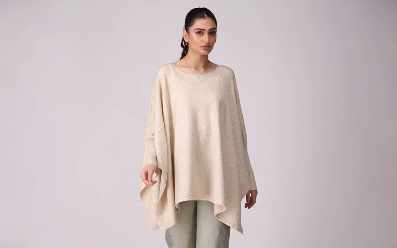 a women wearing cream color cape sweater