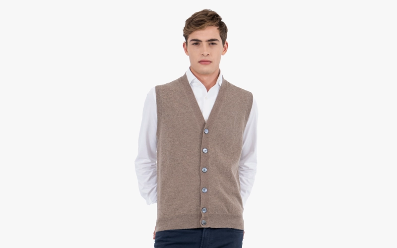 A man wearing a white shirt with a cardigan vest on it
