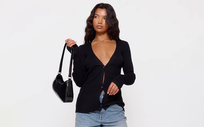a women having a black color bag in her hand wearing a light blur jeans with a dark blue Long Sleeve Cardigan