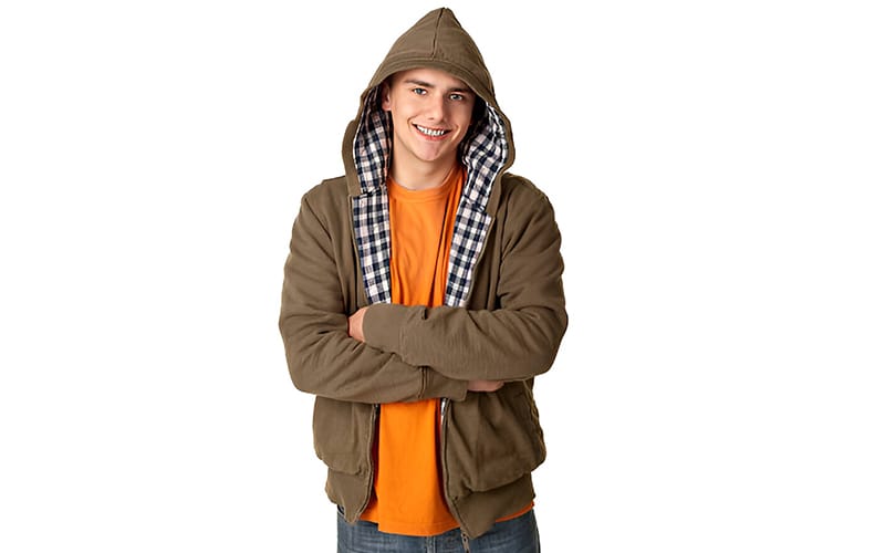 A smiling man wearing a reversible hoodie with a plaid-lined hood, an orange t-shirt underneath, and a casual pose.