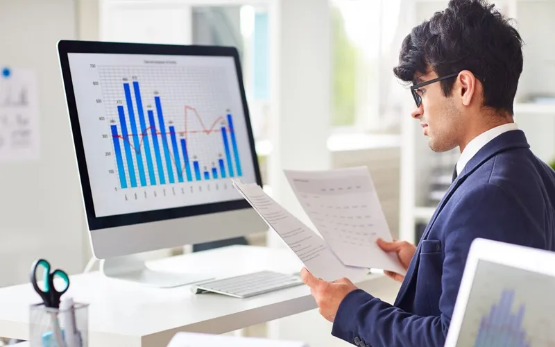 A person analyzing or reviewing operational costs in the management of a clothing line, focusing on ongoing expenses like labor, utilities, and overheads.