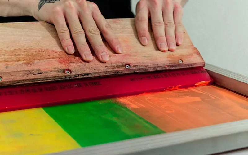 A screen printing press in operation, demonstrating the process of transferring designs onto fabrics through mesh screens, ideal for large runs of high-quality printed garments.