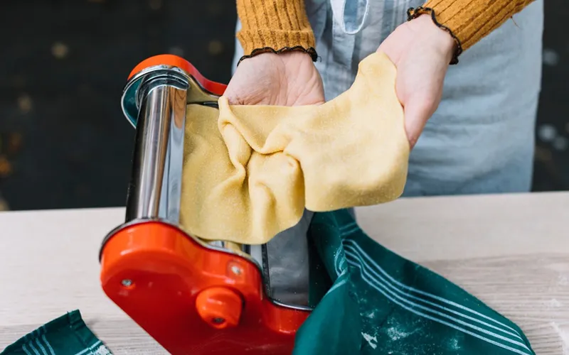 A person working on a fabric project with colorful acrylic fabric, cutting and arranging pieces on a table filled with craft supplies