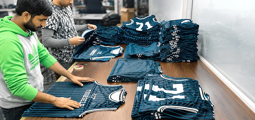 Workers inspecting custom sports jerseys before final production approval
